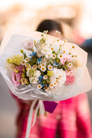 Focus on bouquet of various flowers in white matte wrapping paperの写真素材