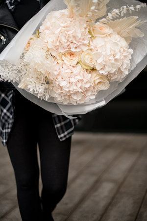 Close up of huge bouquet of white hydrangeas and white roses wrapped in white gift paperの写真素材