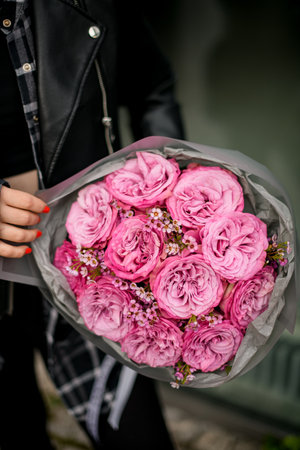 Close up of a bouquet of pink roses with tiny daisies, wrapped in gray wrapping paperの写真素材