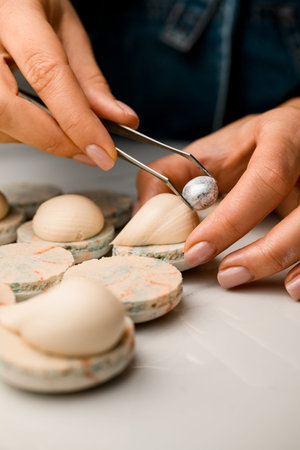 Confectioners female hands decorate a white macaroon with cream with a silver pistachio nutの写真素材