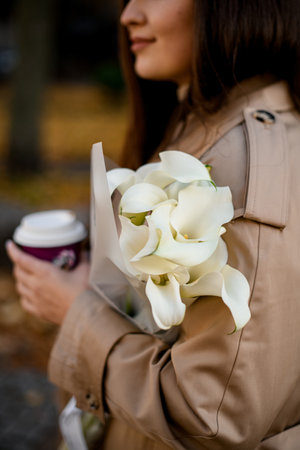 Focus on a bouquet of lilies in the hands of a young pretty womanの写真素材