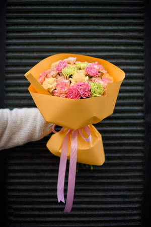 Hands of the girl with a bouquet of carnations on a dark backgroundの写真素材