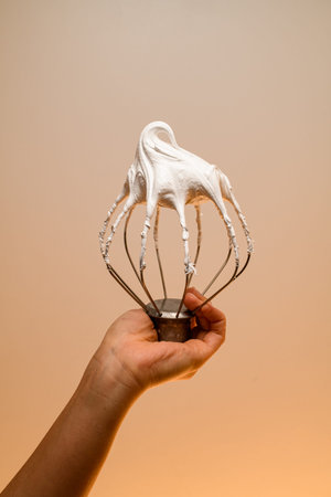 Girls hand with fair skin holding white whipped cream from egg whites