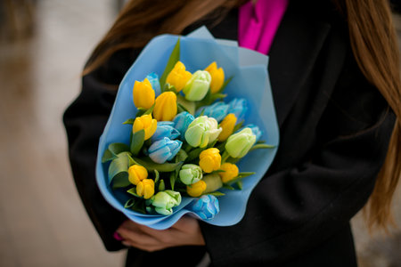 Dark-haired girl in the background with a bouquet of yellow-blue flowersの写真素材