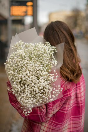 White flowers in bouquet in the hands of a girl standingの写真素材