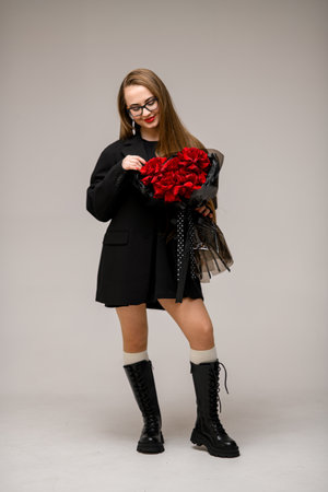 Young pretty smiling woman looking at a bouquet of red roses in black wrapping paperの写真素材