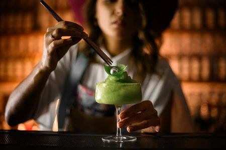 On the bar stands a glass on a tall leg, filled with a smoothie with green ice