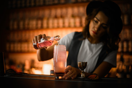 Female bartender is preparing a cocktail, pouring a pink drinkの写真素材