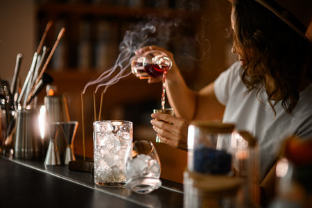 Female bartender prepares a cocktail at the bar, where all the necessary dishes and tools are standingの写真素材