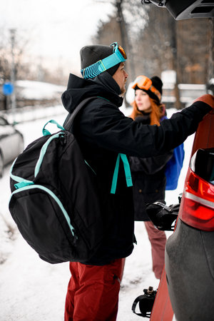 Side view of young man with backpack on his shoulder standing near carの写真素材