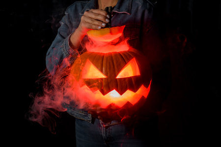 Scary Halloween pumpkin with a carved mouth and eyes in the darkの写真素材