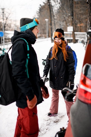 Smiling young man and woman standing with a splitboard and a snowboardの写真素材