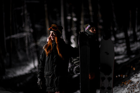 Woman with snowboard, a male snowboarder stands with split board behind herの写真素材