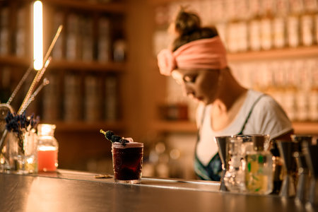 Focus on a glass with a black drink and topped with a skewer with blackberries strung on itの写真素材