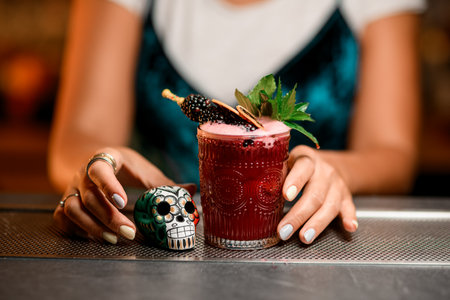 Focus on glass with pink drink decorated with mint leaves, blackberries and orange chipsの写真素材