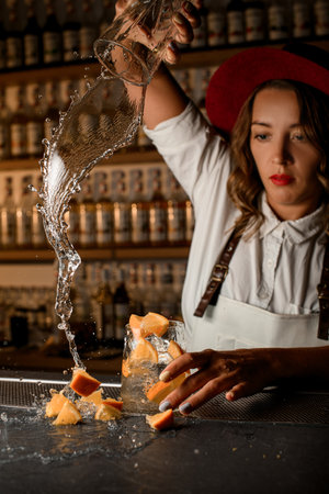 Female bartender poured a clear cocktail with pieces of orange on the barの写真素材