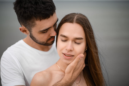 Close-up of the faces of a man and a woman in love. A man stands behind a woman and caresses her face with his handの写真素材