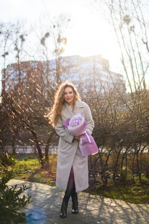 Girl with curly hair staying against the backdrop of nature with a bouquet of flowersの写真素材