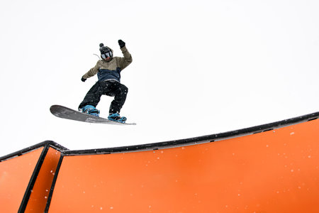 Snowboard pro executes jump into wallride, mastering challenging slope.の写真素材