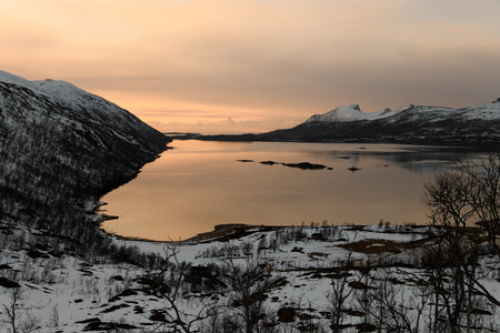 Mountain landscape at sunset. The crimson sky is reflected in the river between the mountainsの写真素材