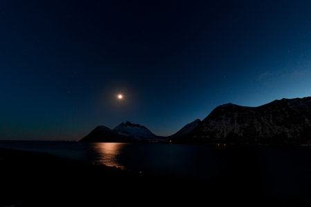 Night shot of beautiful mountains next to a small calm riverの写真素材