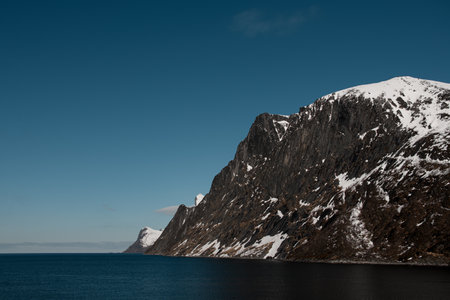 Endless blue sea that stretches to the horizon line next to high rocky mountainsの写真素材