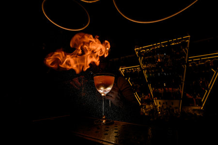 Glass filled with a cocktail stands on a bar counter against the background of drops of spray that igniteの写真素材