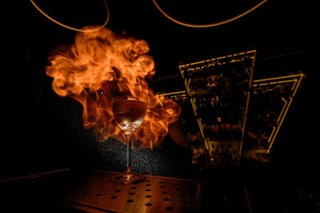 Glass filled with a cocktail stands on the bar counter against the background of drops of spray that catch fireの写真素材