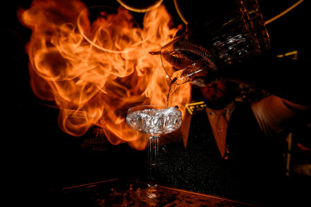 Focus on a cocktail glass into which the bartender sharply pours the prepared drinkの写真素材