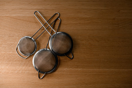 Three fine bartender strainers for straining cocktail components lie on a tableの写真素材