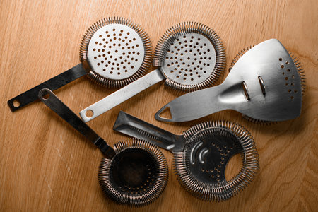 Professional bartender tools, various hawthorns and fine strainers for making a cocktail lie neatly on a surfaceの写真素材