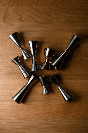 Eight steel jiggers of various sizes and shapes lie on a surfaceの写真素材