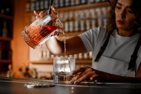 Focus on two glasses for preparing cocktails, in one glass the bartender has mixed the ingredientsの写真素材