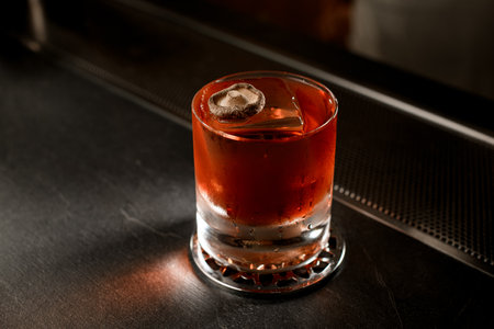 Close-up of a brown iced drink in a transparent glass standing on a metal standの写真素材