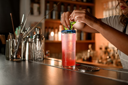 On the bar stands a tall glass with a pink cocktailの写真素材