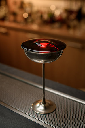 Metal glass with a tall stem up to the crown is filled with a brown drinkの写真素材