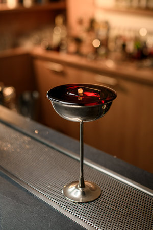 Elegant metal glass with a tall thin stem, filled to the brim with a brown drinkの写真素材