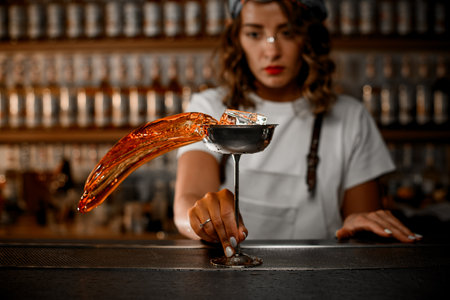 Photo at the moment when a female bartender holds a metal glass by the legの写真素材