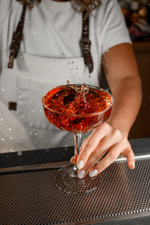 Female bartender placed a glass with a cocktail on the barの写真素材