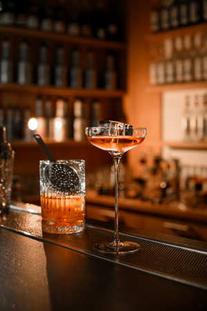 Mixing glass and stemmed glass filled with cocktail on a bar counterの写真素材