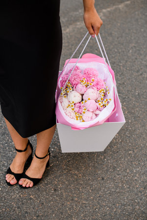 Girl with Bouquet. Black dress, holding beautifully adorned pink flowers.の写真素材