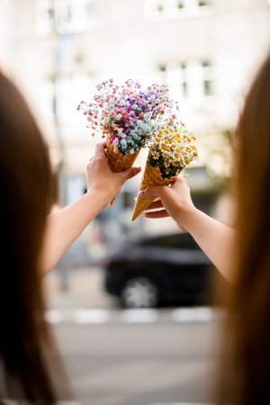 Girls with Flower Cups. Clink glasses amidst waffle cups holding bouquets.の写真素材