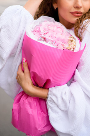 Contemplative Pose. Brown haired woman gazes into distance with flower bouquet.の写真素材