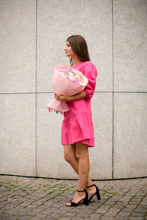 Posing with Pink. Girl in pink dress holds pink flower bouquetの写真素材