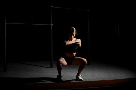 Female athlete doing squats with arms crossed in front of her and palms on her shouldersの写真素材