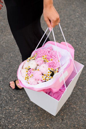 Large gift bag with a bouquet of flowers in womans handsの写真素材