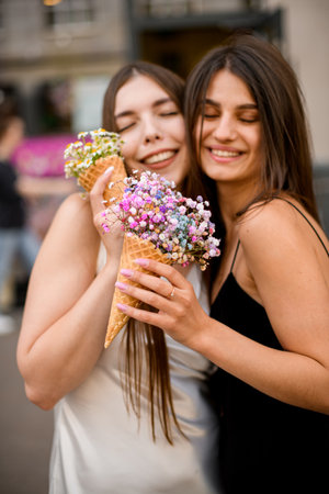 Smiling beautiful girlfriends in a summer dresses with a small bouquetsの写真素材