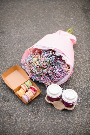 Two glasses of cappuccino, macarons and bouquet of colorful small flowersの写真素材