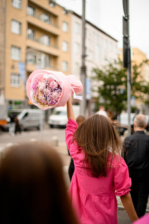 Rear view of confident girl in a pink clothes with a colorful bouquet of flowersの写真素材