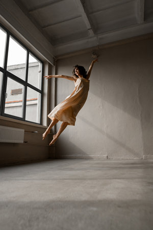 Slender female dancer performing a jump as if flying in the air like a birdの写真素材